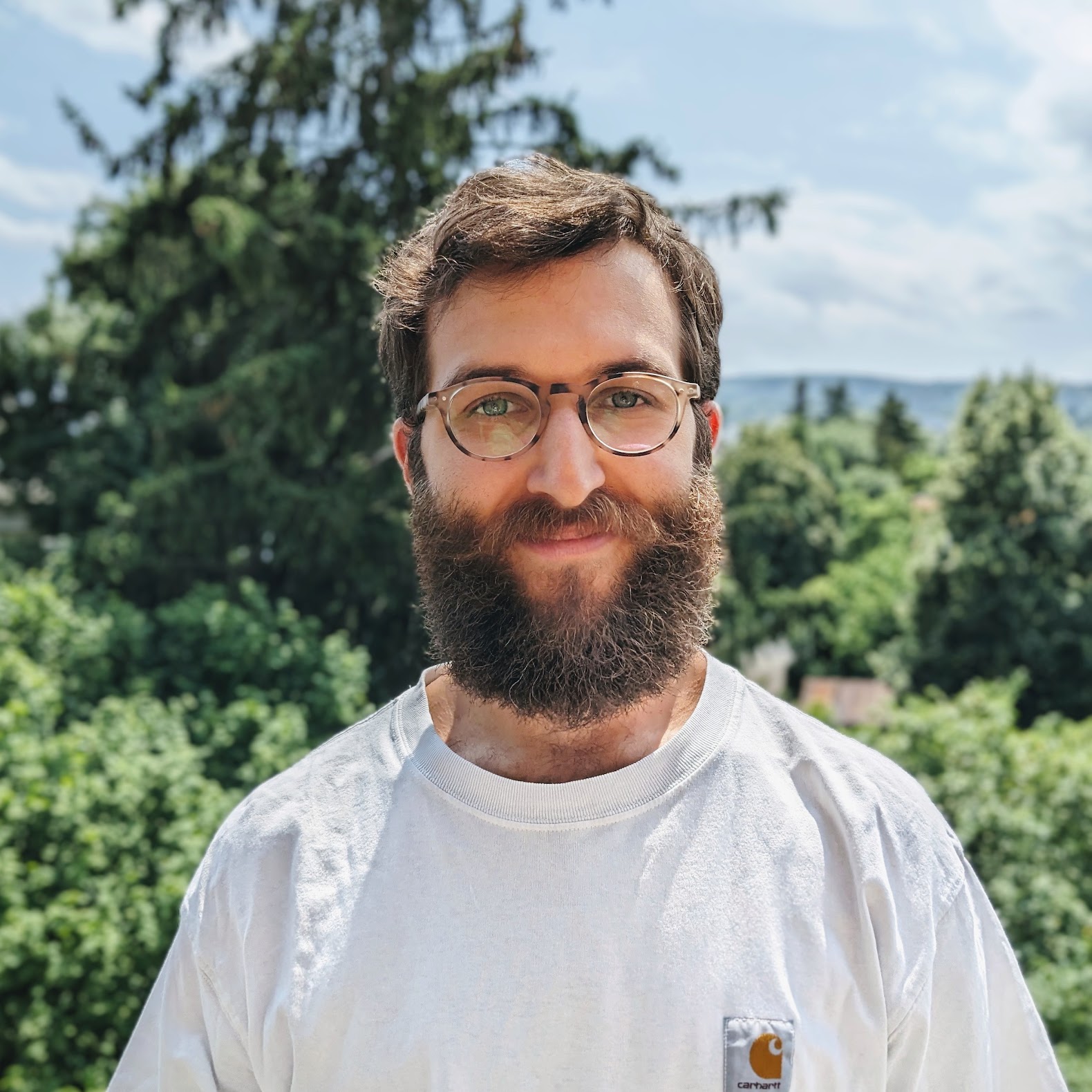 A photo of me smiling. I have round glasses, short brown hair and a short beard.